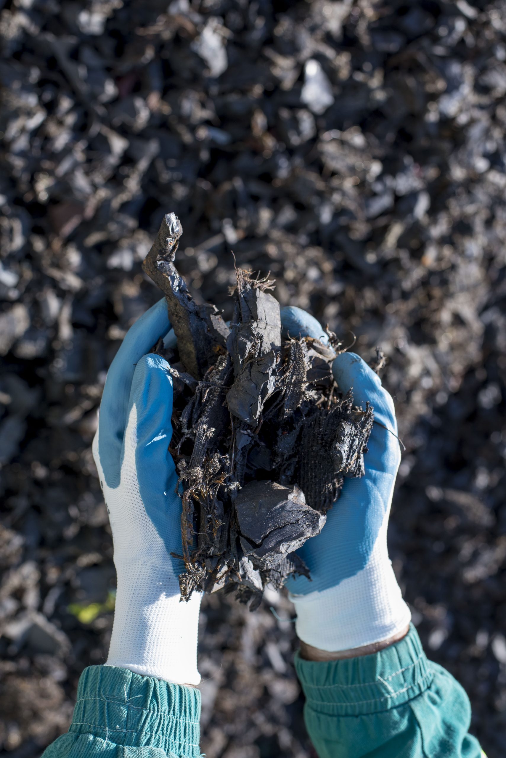 A hands of a person holding a handful of shredded tires